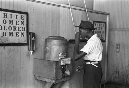 有色人種専用の水飲み場で水を飲む黒人男性（1950年代）／Wikipediaより引用